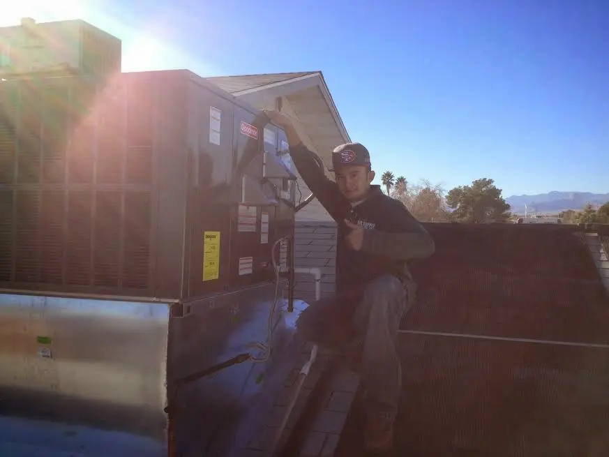 HVAC technician performing Air Duct Cleaning on a rooftop unit in Azle